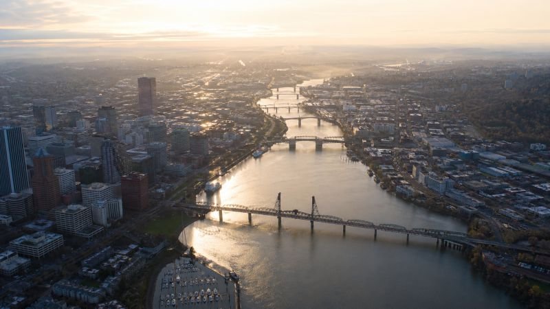 Aerial view of a river winding through a dense urban area with multiple bridge crossings along the river corridor.