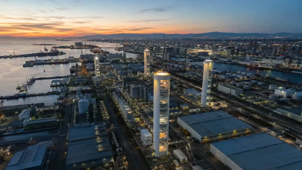 Carbon Sequestration Towers integrated into a near-future industrial port city with waterfront infrastructure, storage tanks, and illuminated capture towers at dusk.