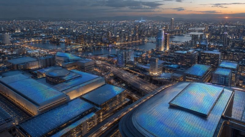 Dense urban landscape at dusk with rooftops and building surfaces covered by subtle iridescent quantum flux harvesting coatings