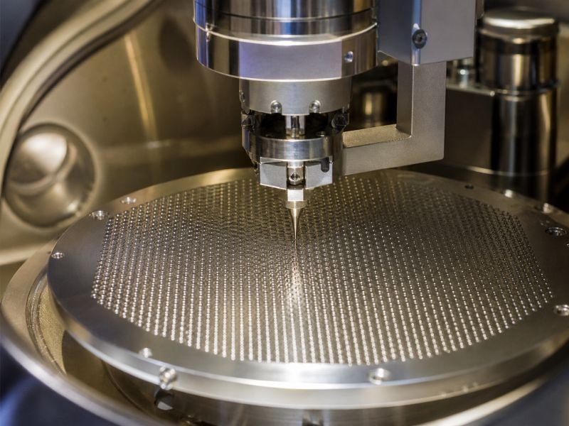 Scanning tunneling microscope probe hovering above an ordered metallic surface lattice inside a clean research instrument.