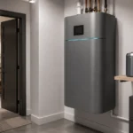 Personal fusion energy cell installed in a modern home utility room with a wall-mounted matte grey power unit, status strip, touchscreen panel, and nearby fuel cartridge