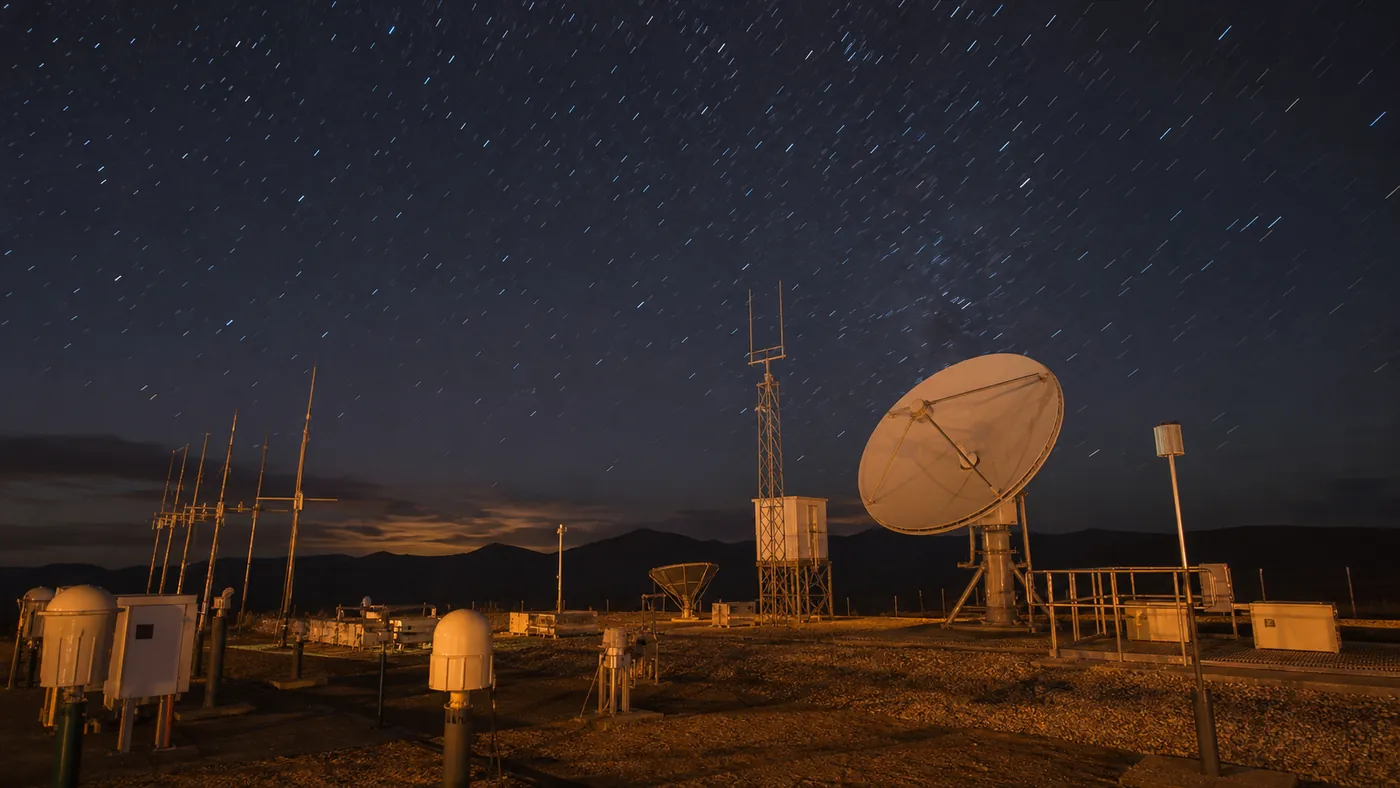 Solar physics monitoring station with radio dishes and scientific antenna arrays under a clear night sky